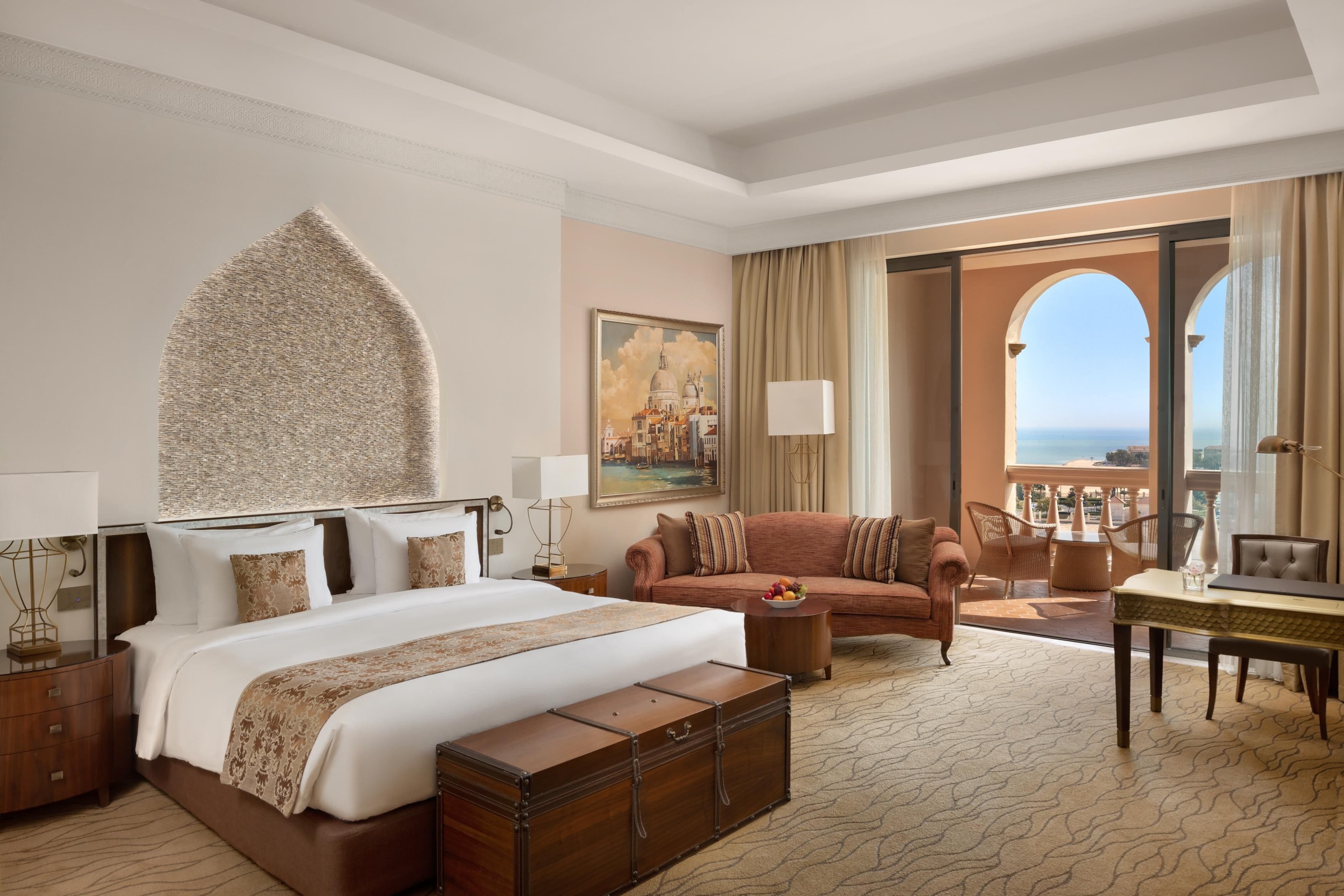 Habitación de hotel con una cama grande, un sofá, una mesa de comedor y vistas al mar.