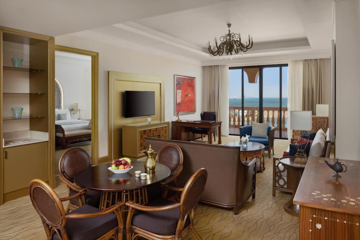 Une chambre d’hôtel comprenant un coin repas, un ensemble de canapés, une télévision et une vue sur la mer.