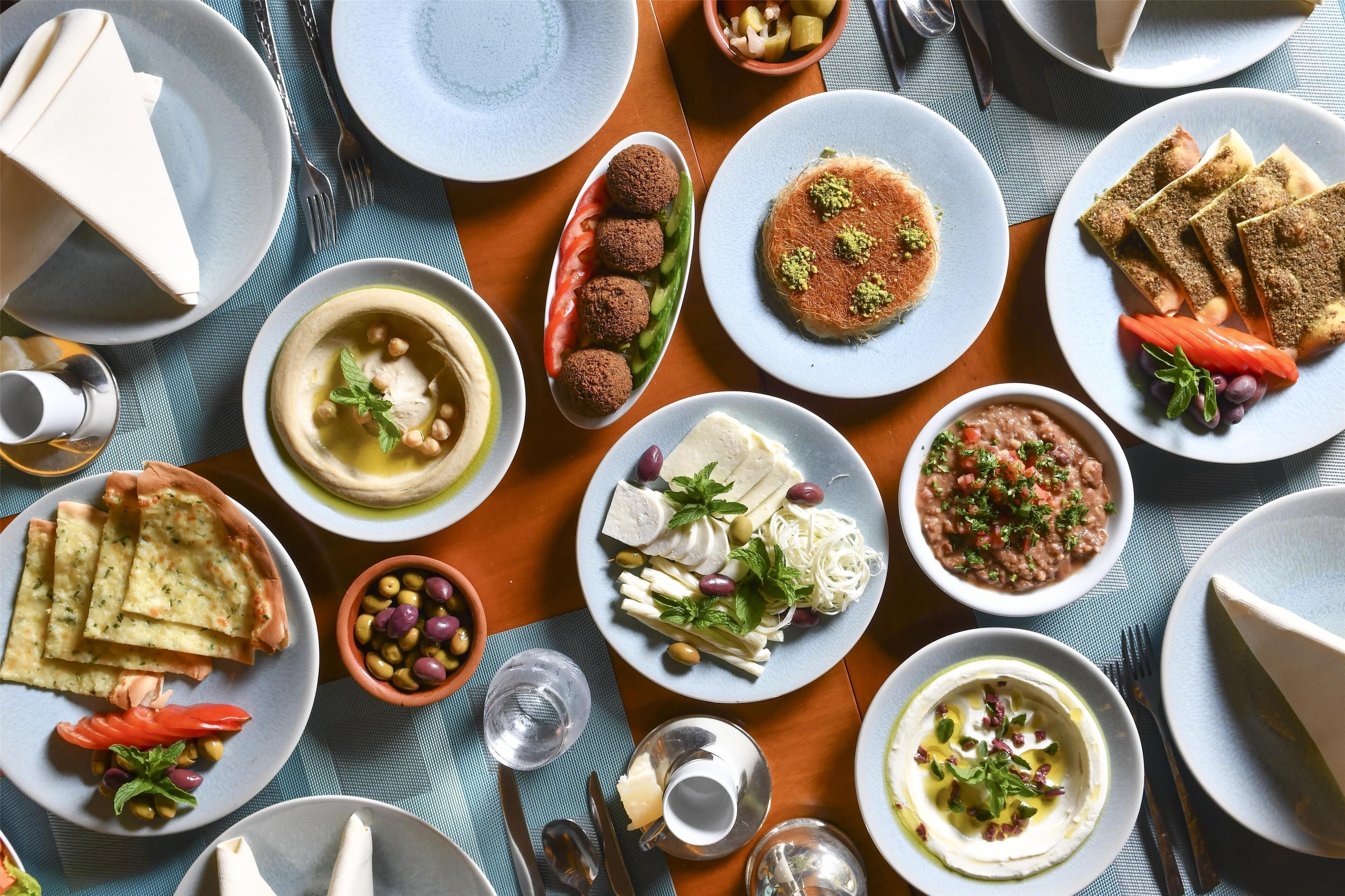 A variety of dishes on a table, including falafel, hummus, and flatbread.
