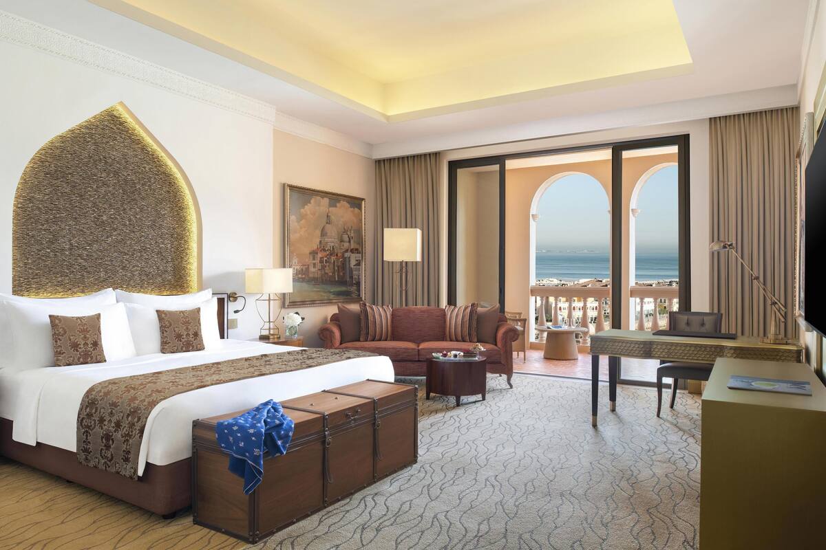 Une chambre d’hôtel avec un grand lit, un canapé, un bureau et une vue sur la mer.