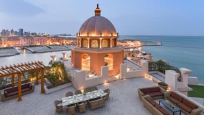 A rooftop terrace with a central dome structure, outdoor seating, and a view of the city skyline and sea.