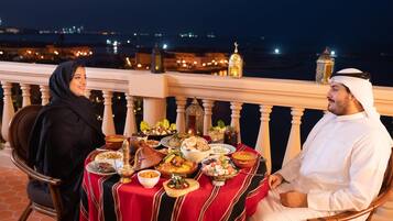 A dining table with a variety of dishes and a cityscape view in the background.