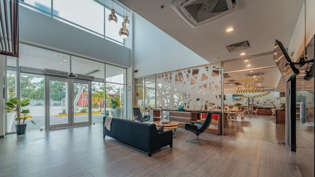 Un interior de restaurante moderno con una zona de recepción, asientos y vistas al exterior.