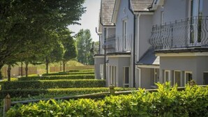 A two-story house with a balcony, surrounded by well-maintained hedges and trees. - Wolseley Holiday Lodges (Tullow)