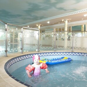 A child in a swimming pool with a blue inflatable toy.