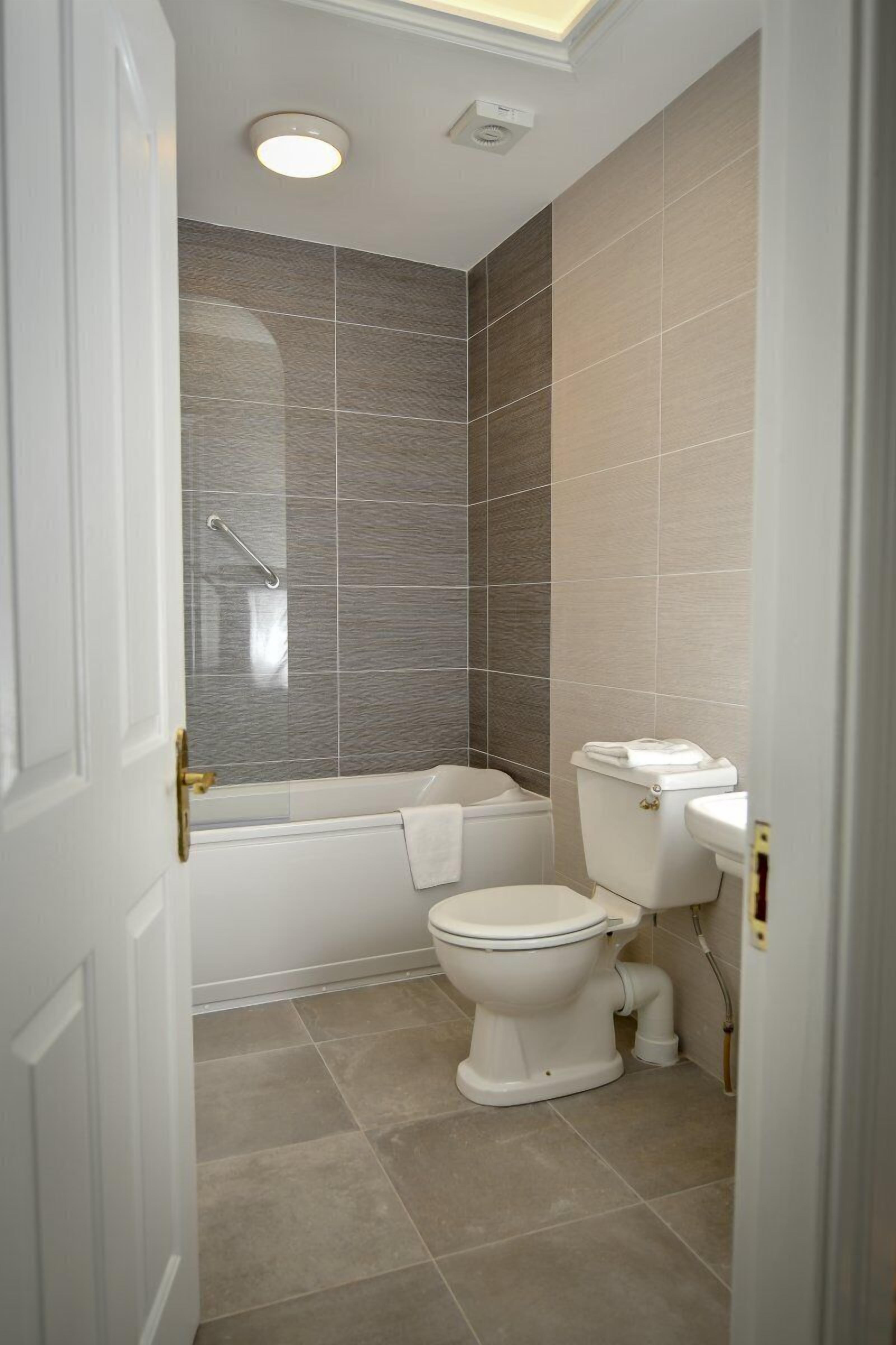 A bathroom with a bathtub, toilet, and a shower area.