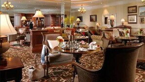 A spacious hotel lobby with a high ceiling, chandeliers, and a central seating area with tables and chairs. - Wolseley Holiday Lodges (Tullow)