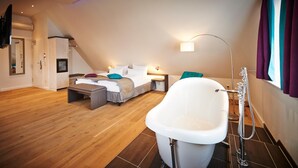 Un dormitorio moderno con una cama grande, una zona de estar y un baño separado con bañera.