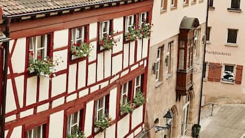 A traditional half-timbered building with multiple windows, some with flower boxes, and a street in front.