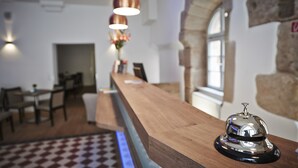 Un área de recepción con un mostrador de madera, un timbre y una pared de piedra.