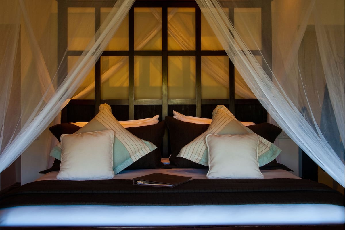 A bed with a canopy, pillows, and a book.