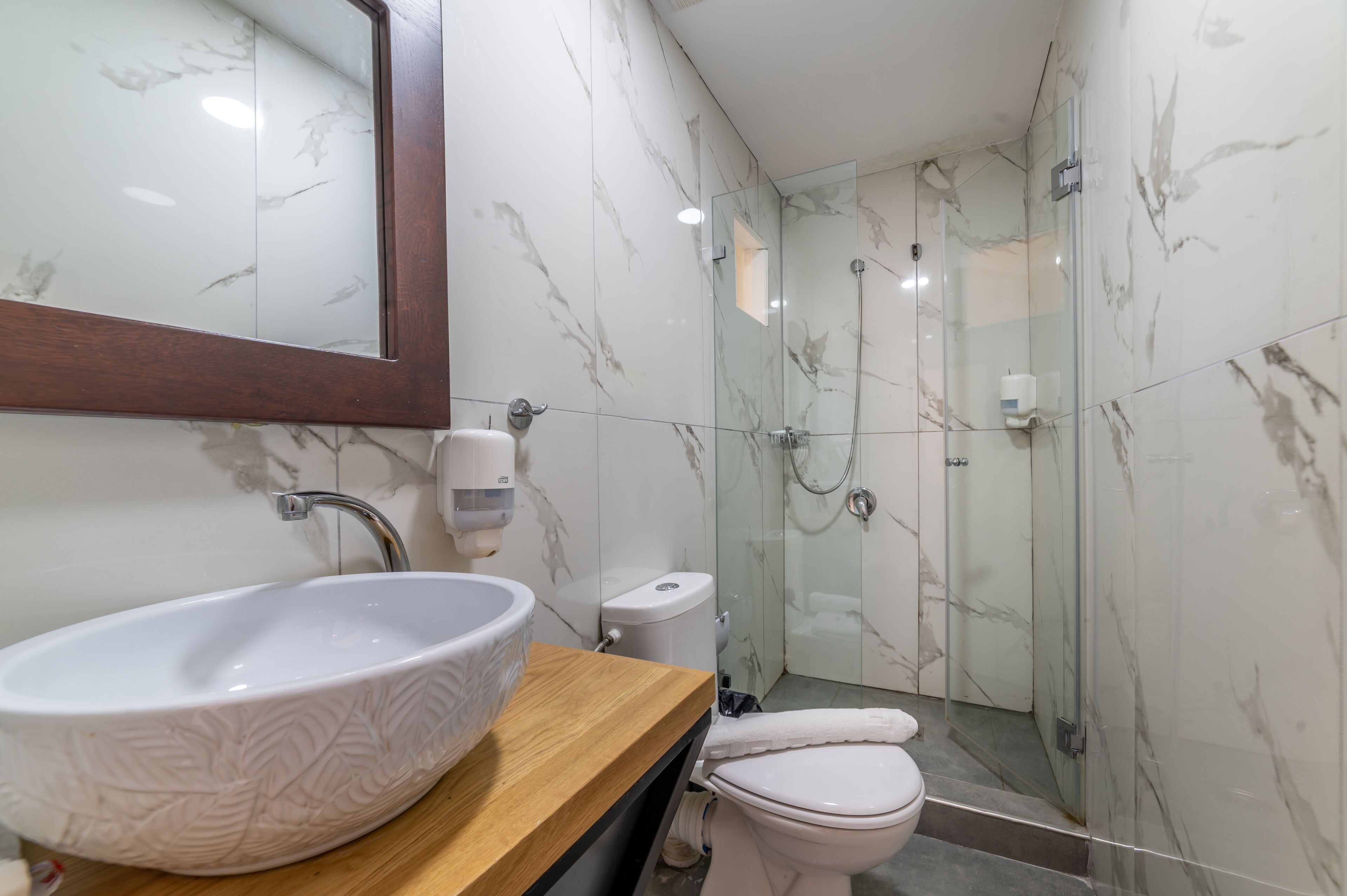 Ein Badezimmer mit Marmorwaschbecken, Toilette und Duschkabine aus Glas.