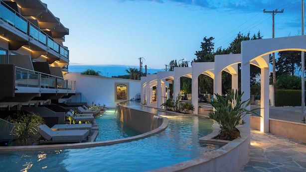 A pool area with lounge chairs and a view of the ocean.