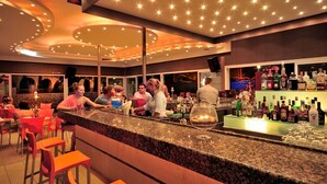 A bar area with a counter, seating, and a variety of bottles.