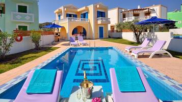 A swimming pool with lounge chairs, a bar area, and a view of a large building with balconies.