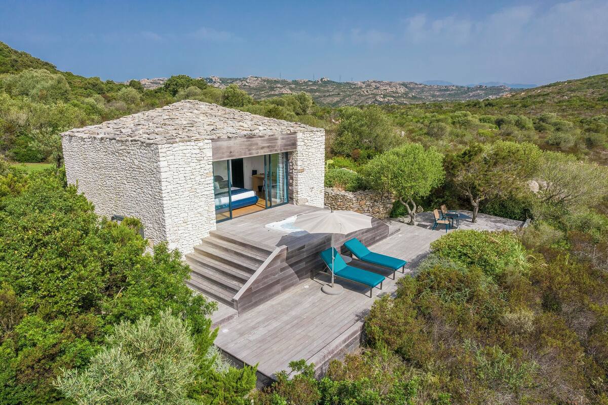 Une maison en pierre dotée d’une terrasse et d’un espace salon extérieur.
