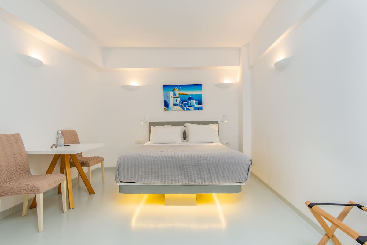 A modern bedroom with a bed, a desk, and chairs.