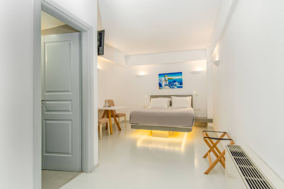 A modern bedroom with a bed, bedside table, and a painting on the wall.