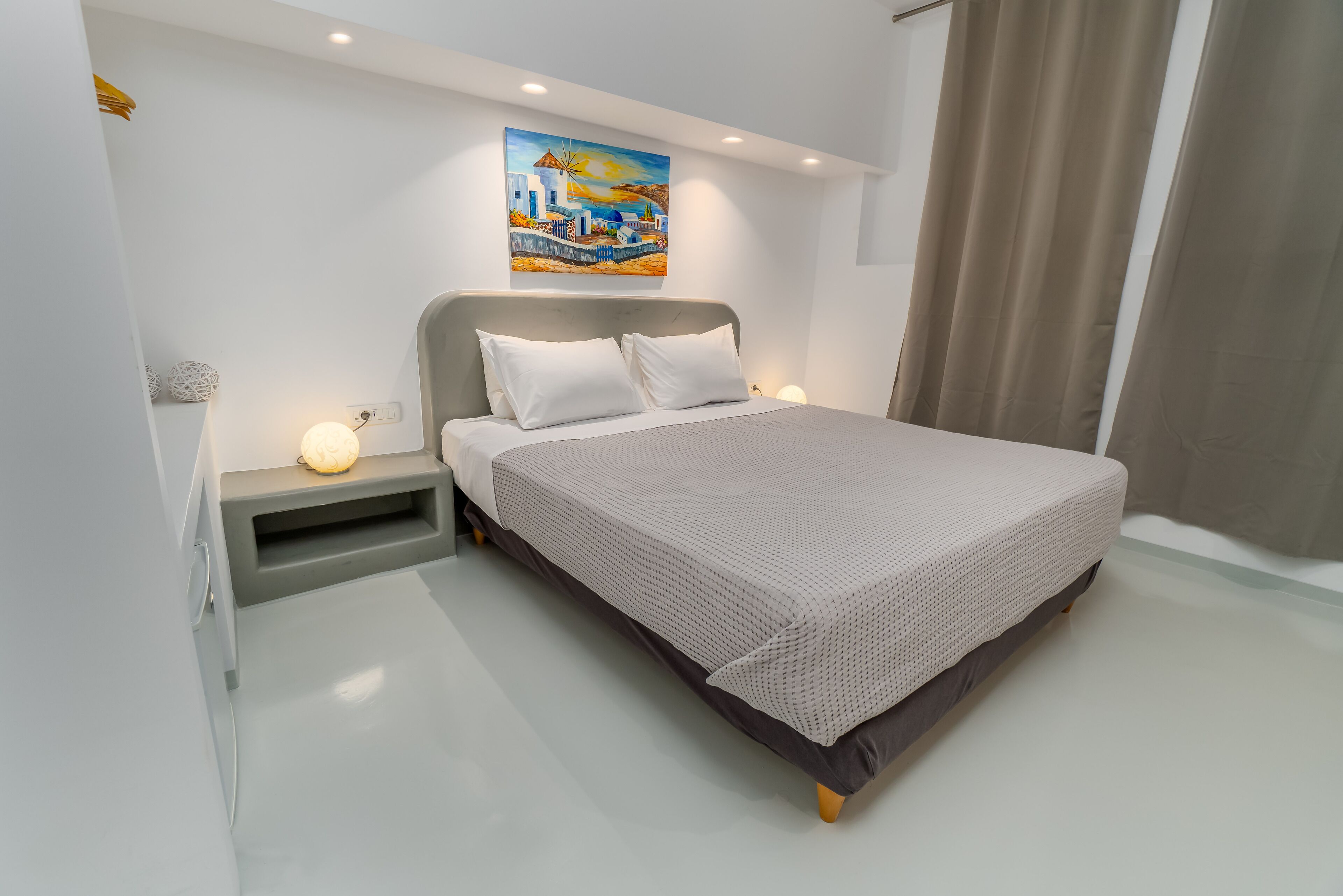 A modern bedroom with a large bed, a nightstand, a wall-mounted painting, and a window with curtains.
