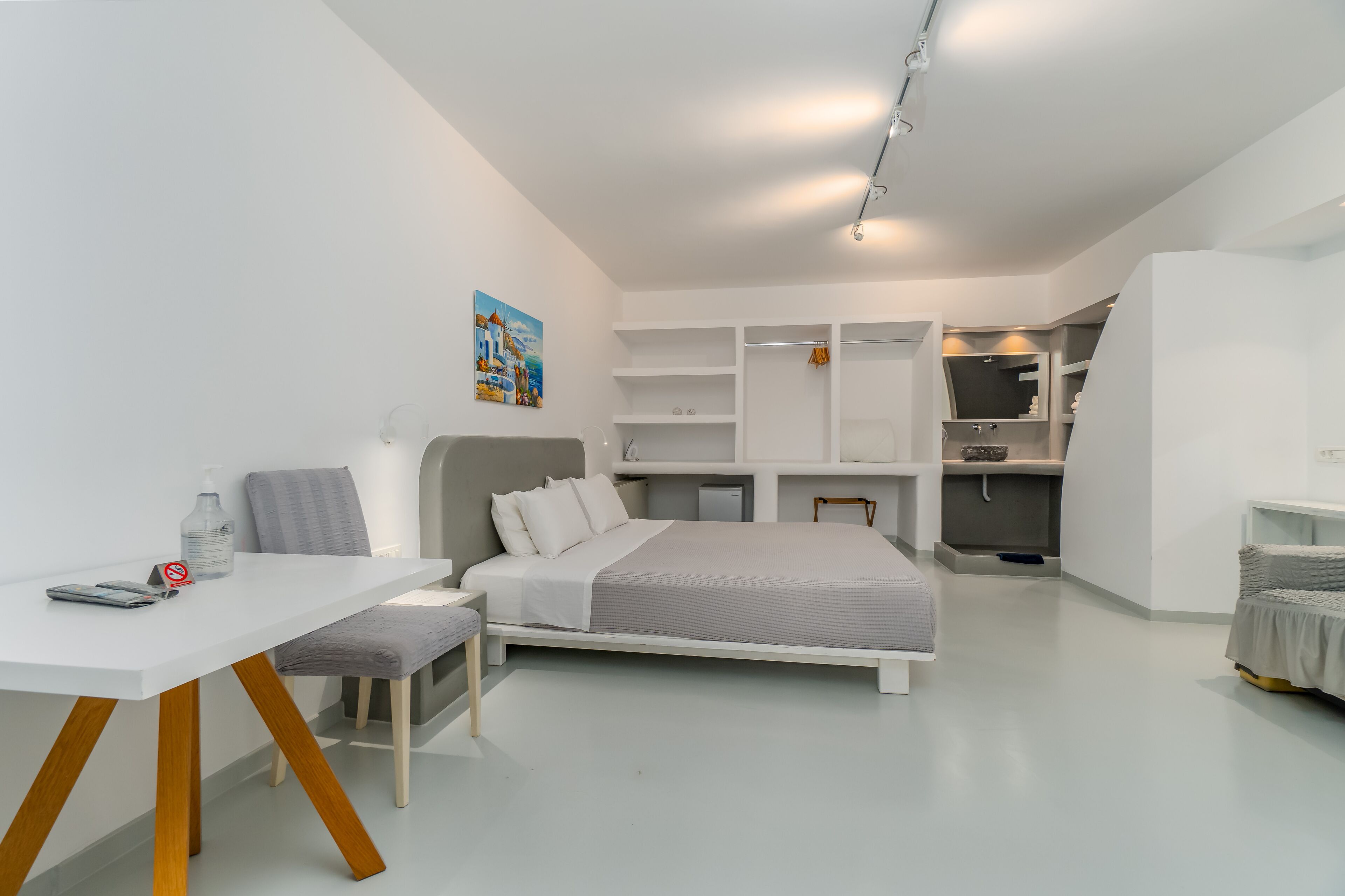 Een moderne, goed verlichte slaapkamer met een bed, nachtkastje en bureau.