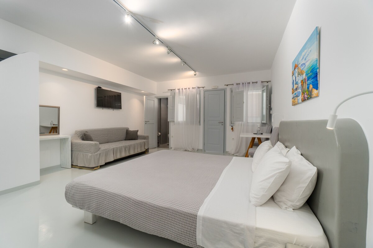 Un dormitorio moderno con una cama grande, un sofá, un escritorio y un cuadro en la pared.