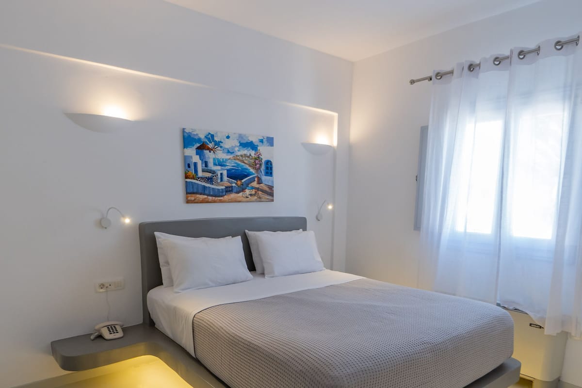 A modern bedroom with a bed, bedside tables, and a painting on the wall.