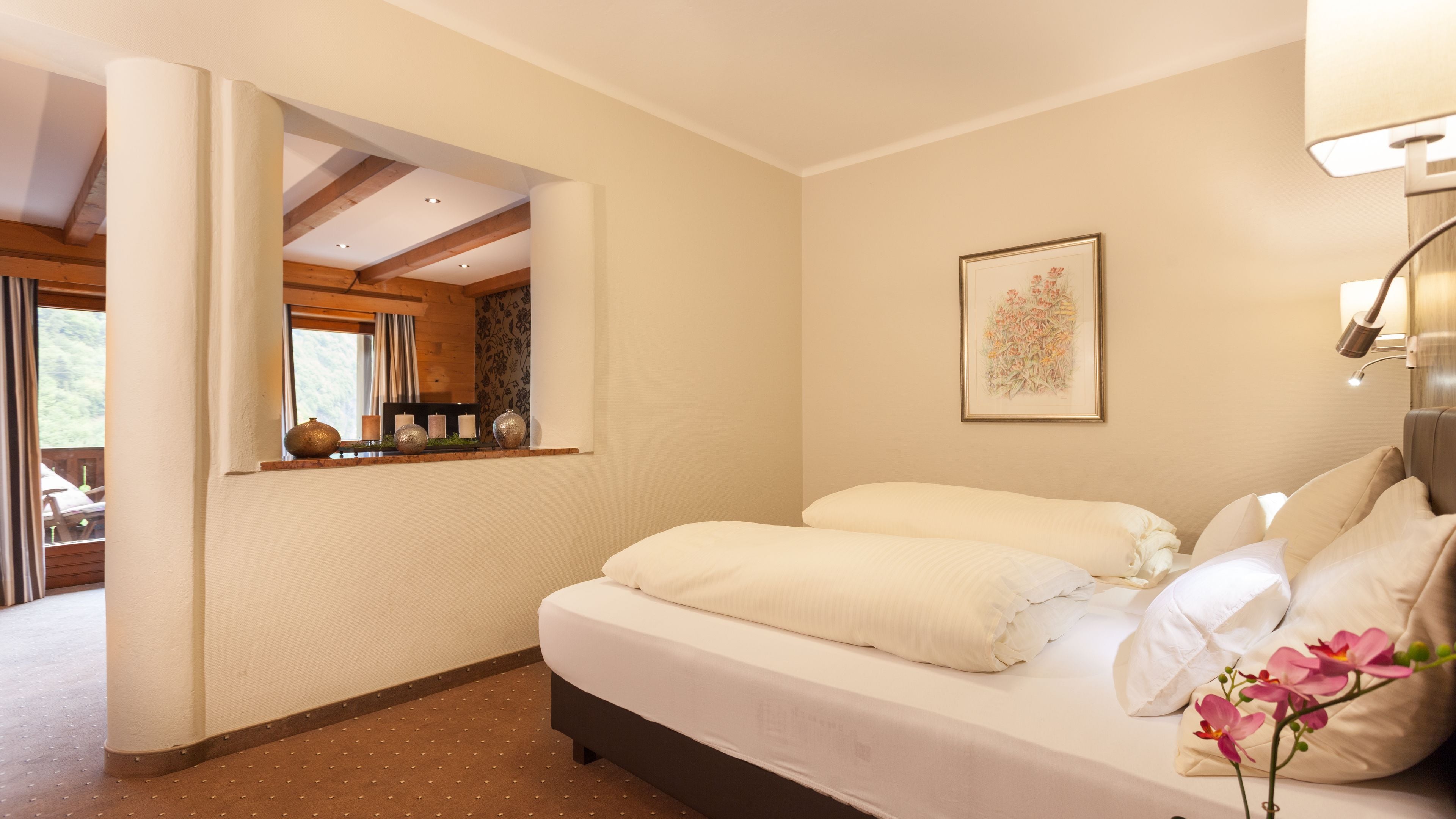 Ein Schlafzimmer mit Bett, Fenster mit Blick, einem gerahmten Bild an der Wand und einer Lampe.