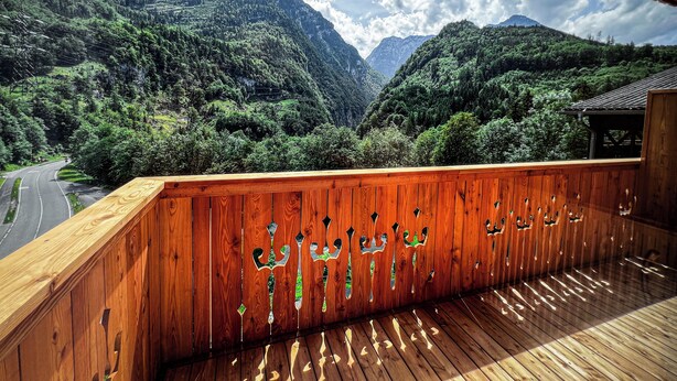 Une terrasse en bois offrant une vue sur un paysage montagneux.