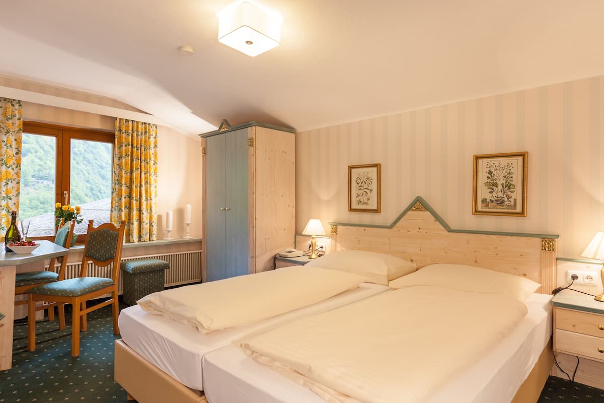 Een hotelkamer met een bed, een bureau, een stoel, een lamp en een raam met gordijnen.