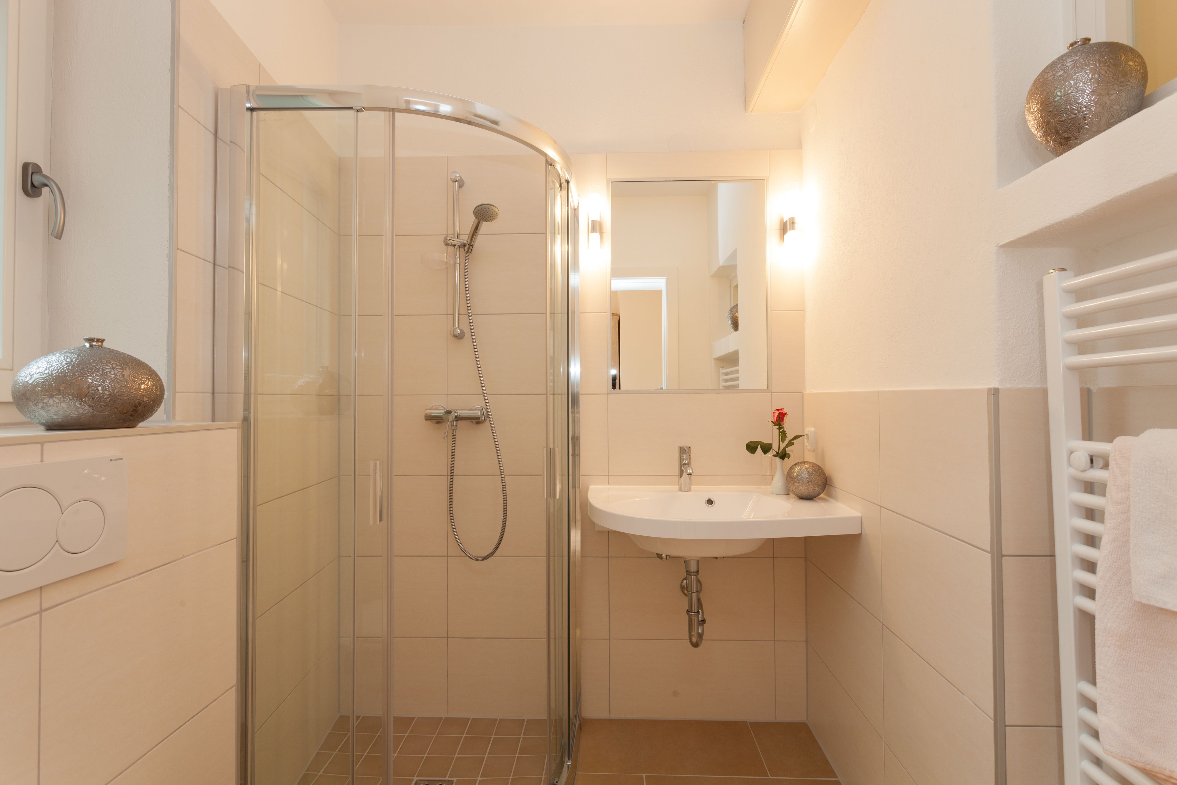A modern bathroom with a glass-enclosed shower, a white sink, and a towel rack.