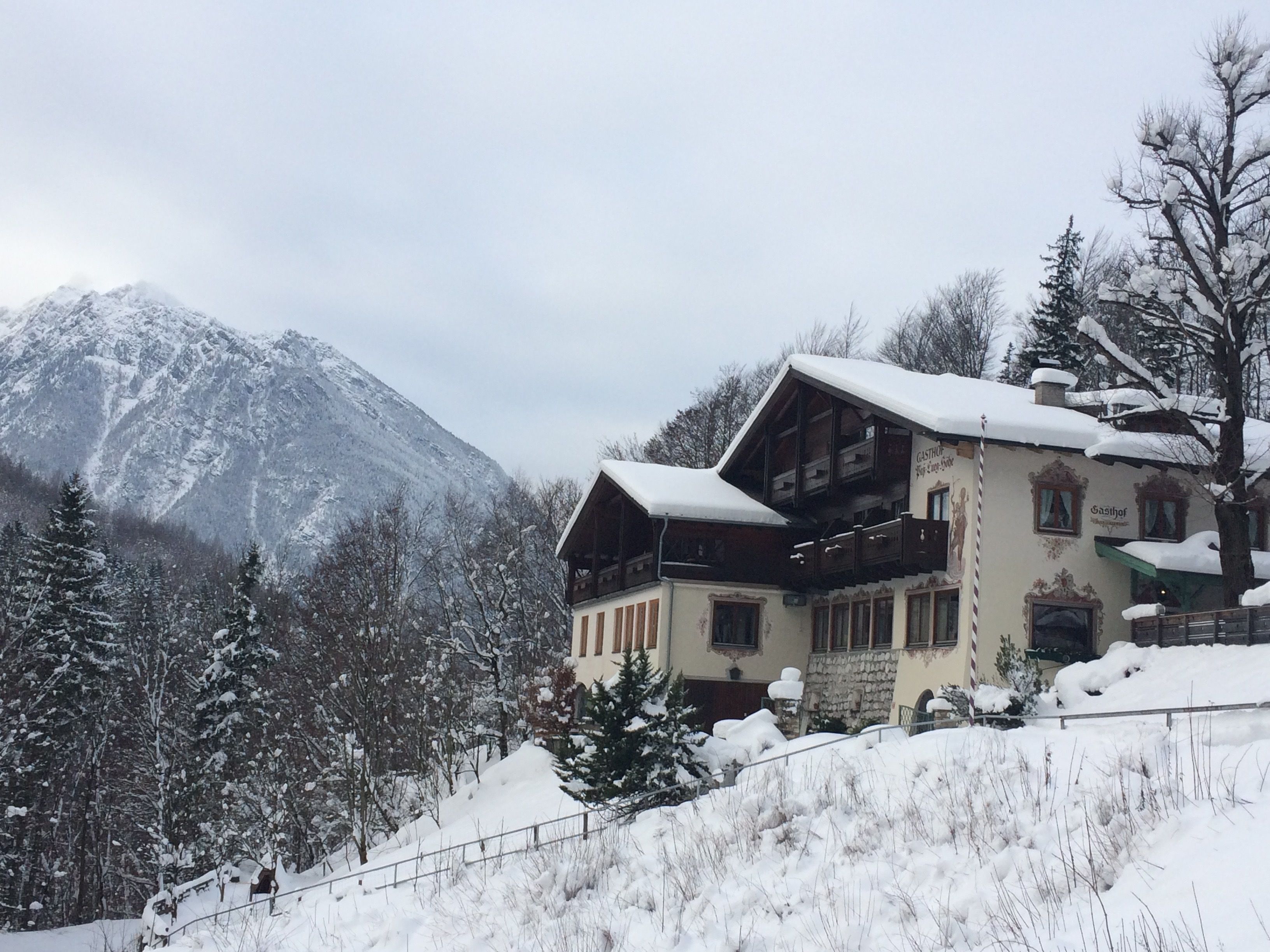 Un edificio de estilo chalete tradicional con techo inclinado, balcones de madera y un paisaje de montaña al fondo.