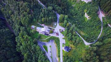 An aerial view of a road network with a building complex, surrounded by dense forest.