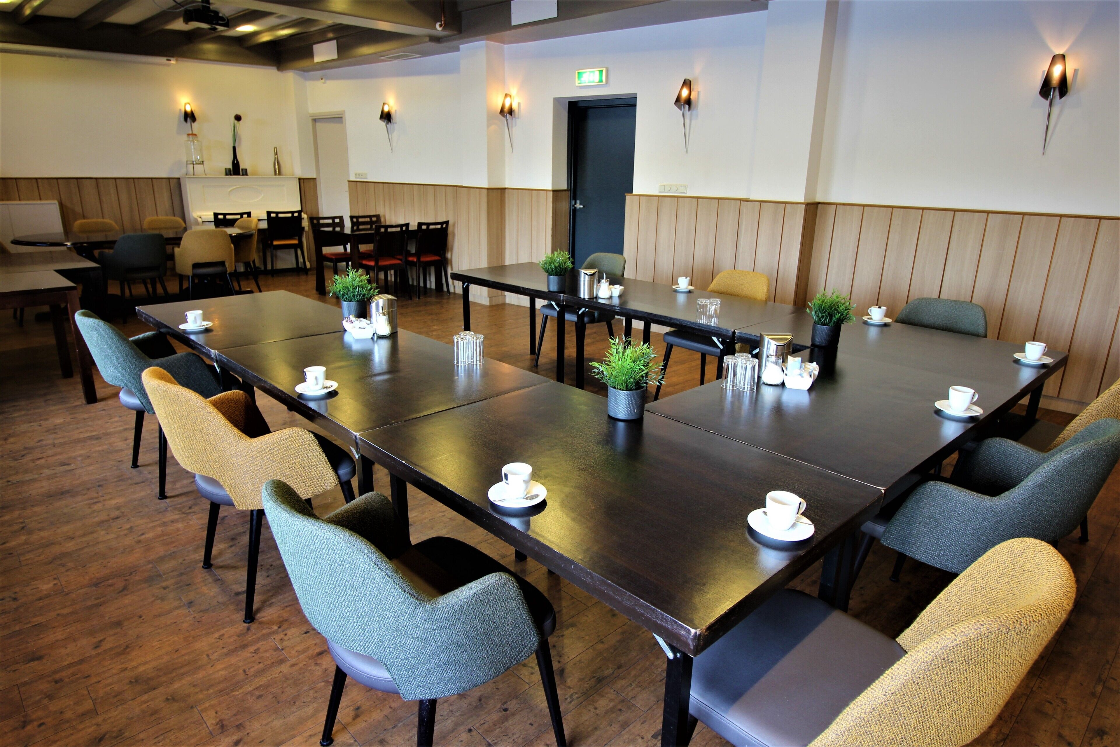 Une salle de conférence avec une longue table, des chaises et des plantes en pot.