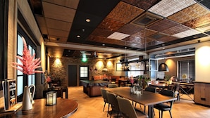 Een modern restaurant met een houten vloer, een bar en een eetgedeelte met tafels en stoelen.
