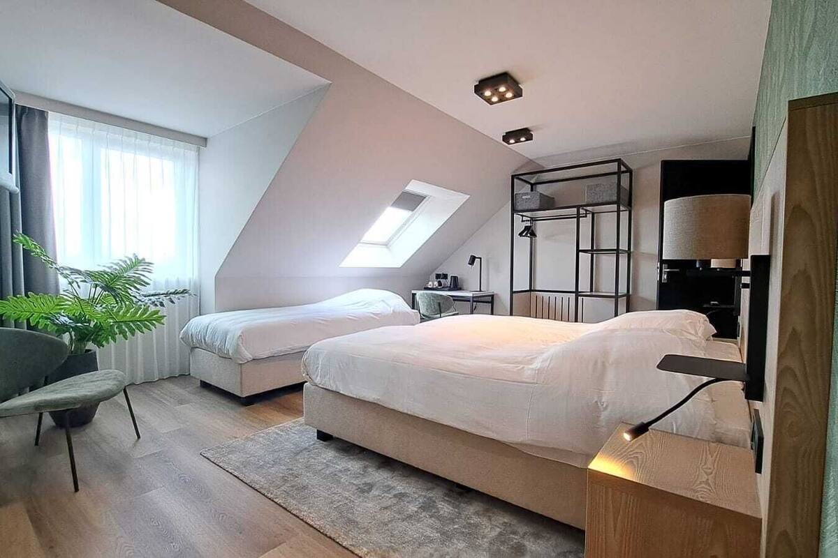 Een moderne slaapkamer met twee bedden, een dakraam, een bureau en een stoel.