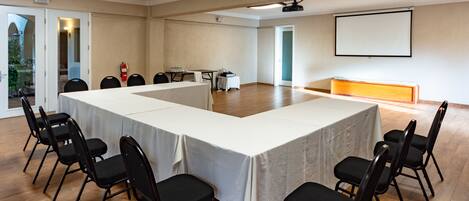 A conference room with a long table, black chairs, a projector screen, and a whiteboard.