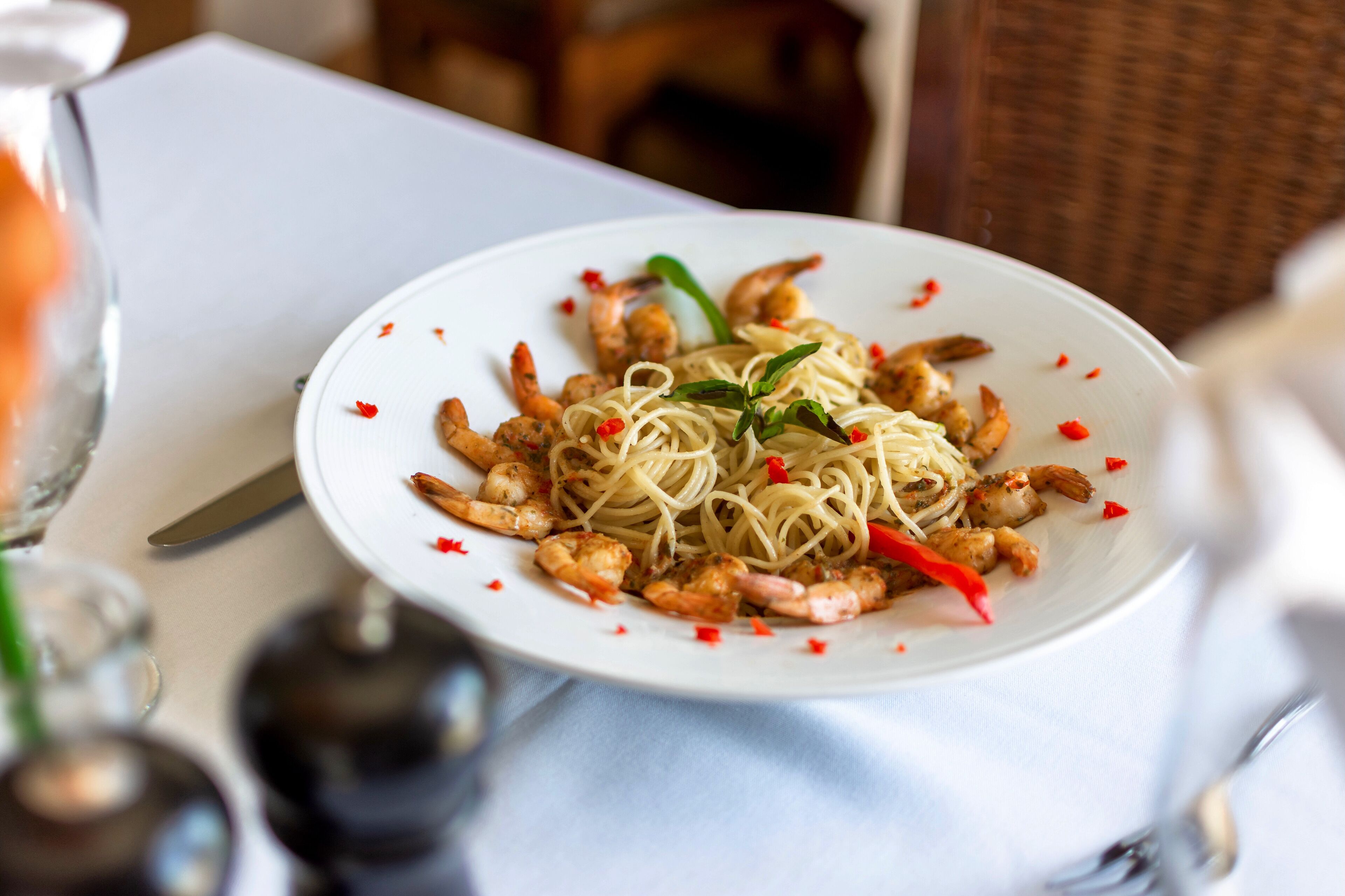 Un plato de espagueti con camarones y hojuelas de chile rojo.