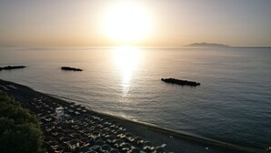 Una platja amb aigua banyada pel sol, gandules i ombrelles.