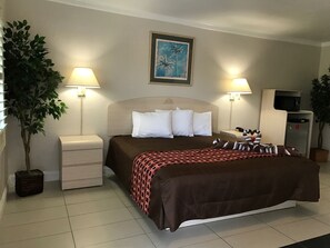 Relax in a cozy space with a comfortable bed, nightstand, and wall-mounted TV.
