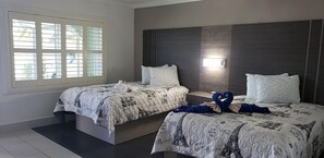 A hotel room with two beds, a large window, and a dark headboard. - Apollo Inn Motel (Cocoa)