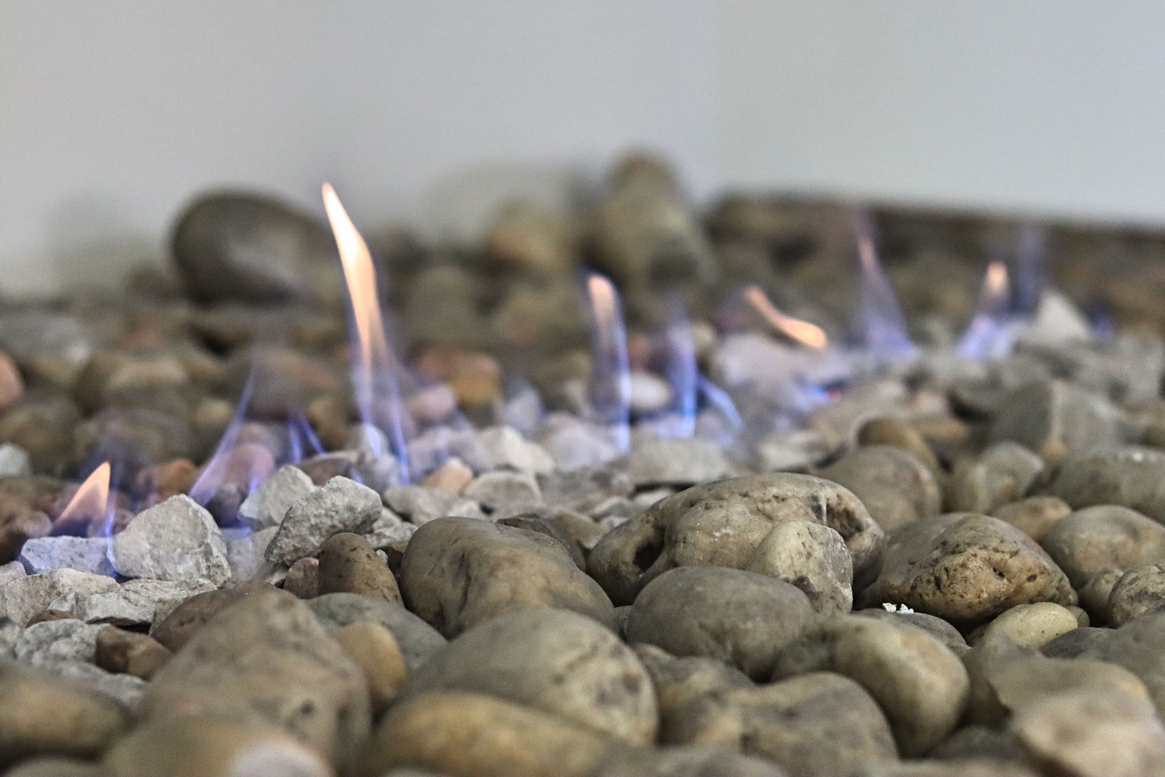 A close-up of a fire burning on a bed of rocks.