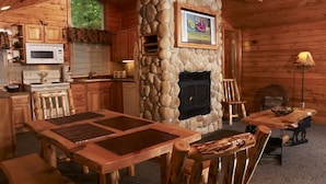 A cozy cabin-style interior with a stone fireplace, wooden furniture, and a kitchen area. - Yogi Bear's Jellystone Park Camp-Resort Wisconsin Dells (Wisconsin Dells)