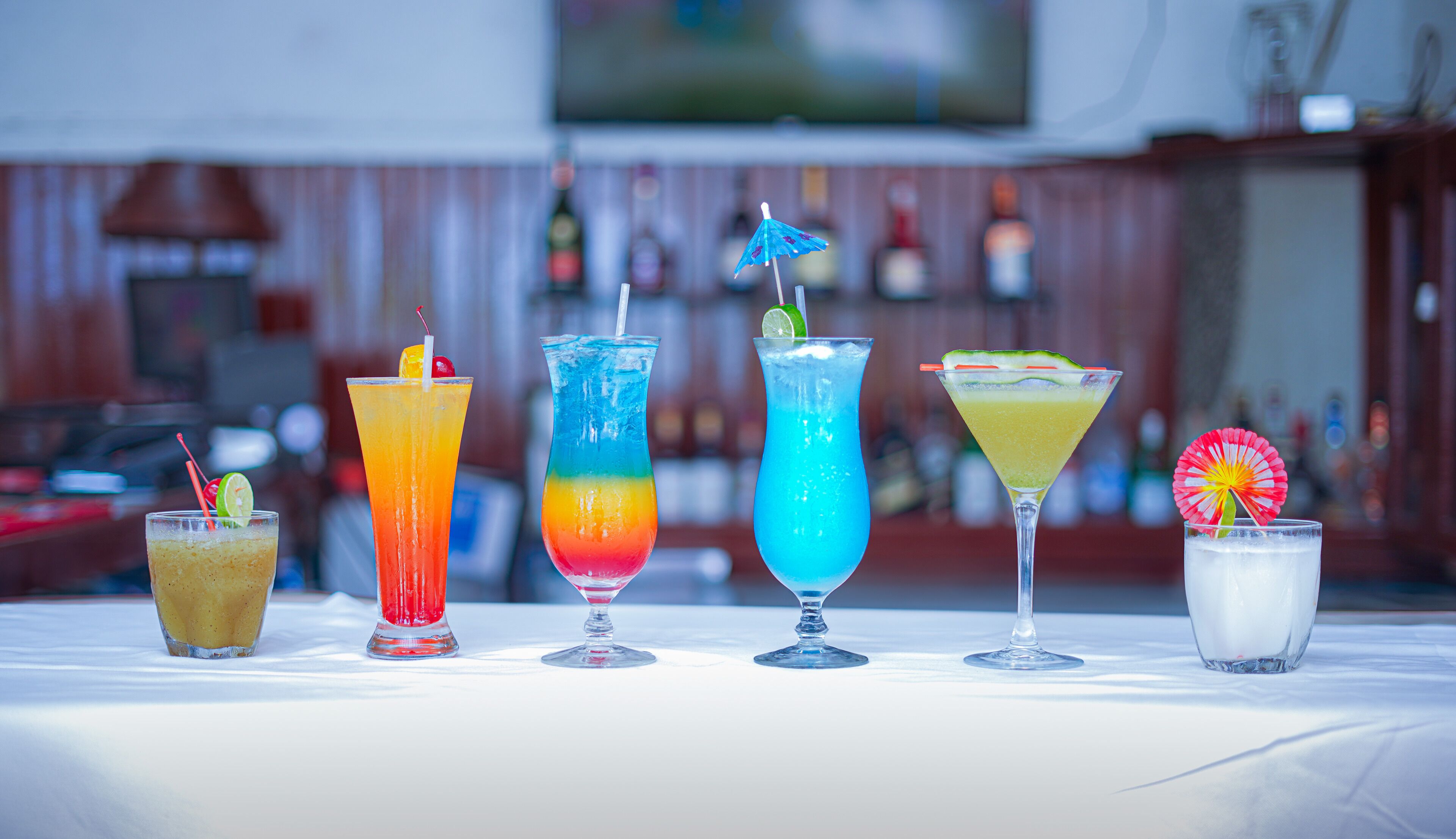 A bar with a variety of colorful cocktails on a white table.