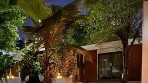 An outdoor dining area with tables set for two, each with white tablecloths and candles. - Visa Lodge (Port-au-Prince)
