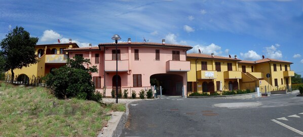 A row of yellow and pink buildings with a street in front.