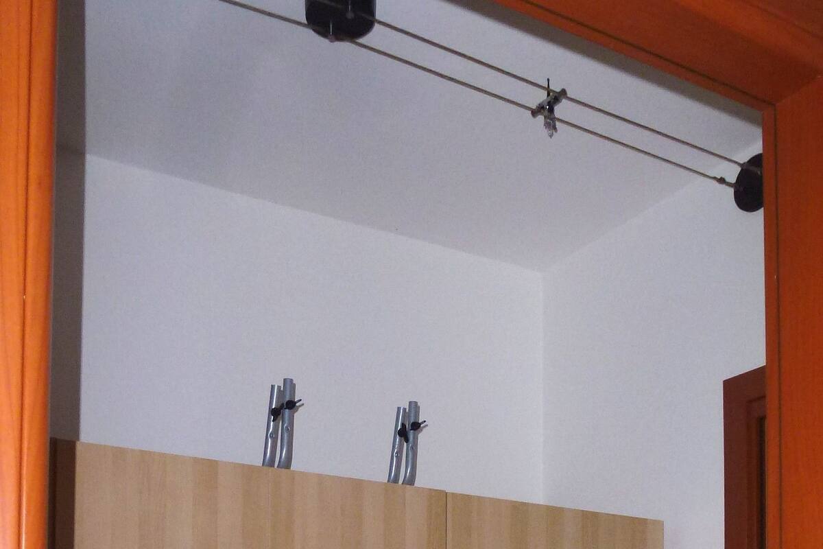 Une armoire en bois à deux portes et dotée d’un petit tiroir, un luminaire fixé au plafond et une poignée de porte.