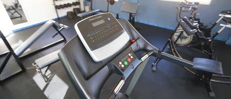A gym with cardio equipment, weight machines, and dumbbells.