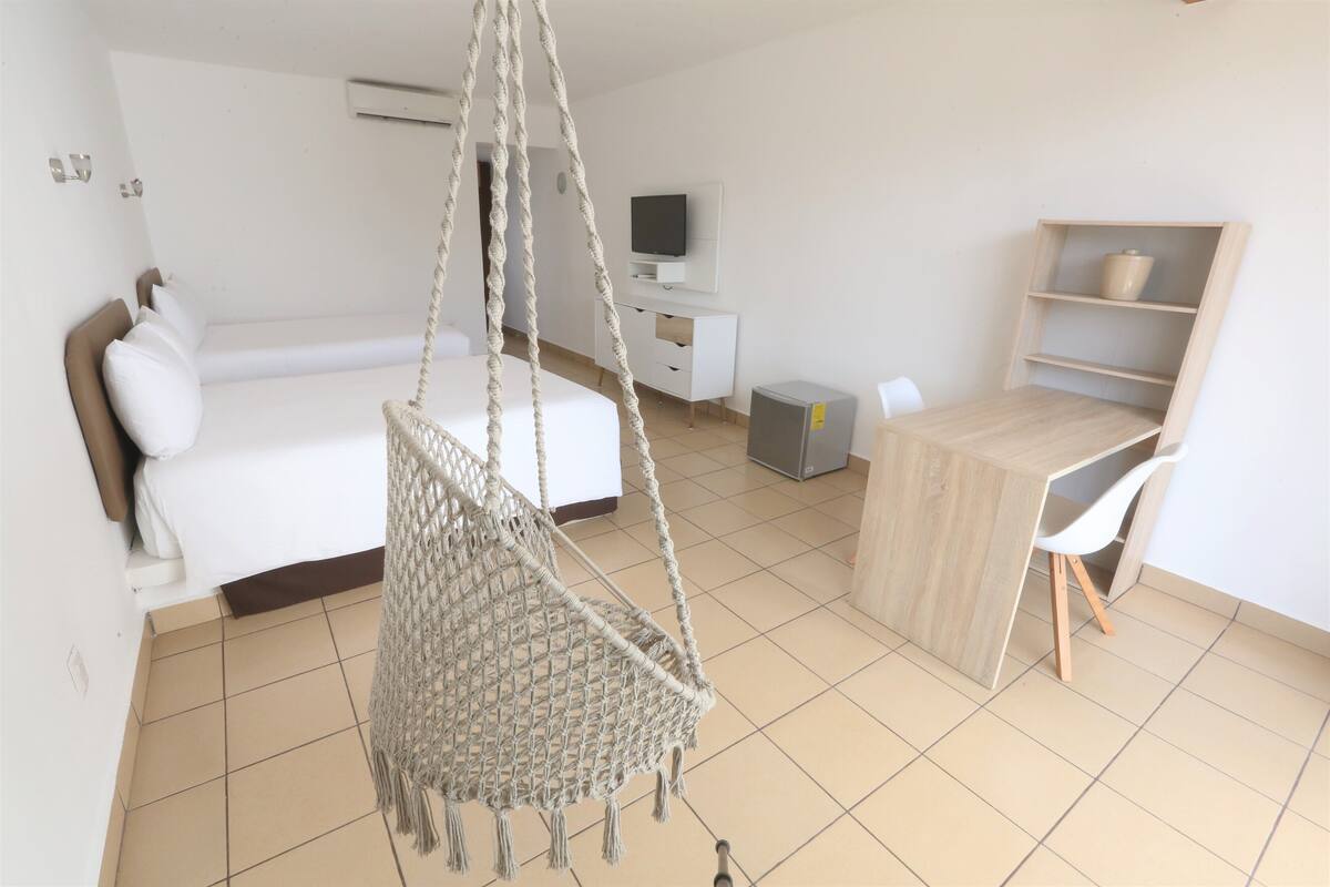 Une chambre à coucher avec un lit, un fauteuil suspendu, un bureau et un téléviseur.
