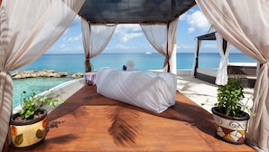 Un dormitorio frente a la playa con vista al océano, una cama y dos plantas en macetas.