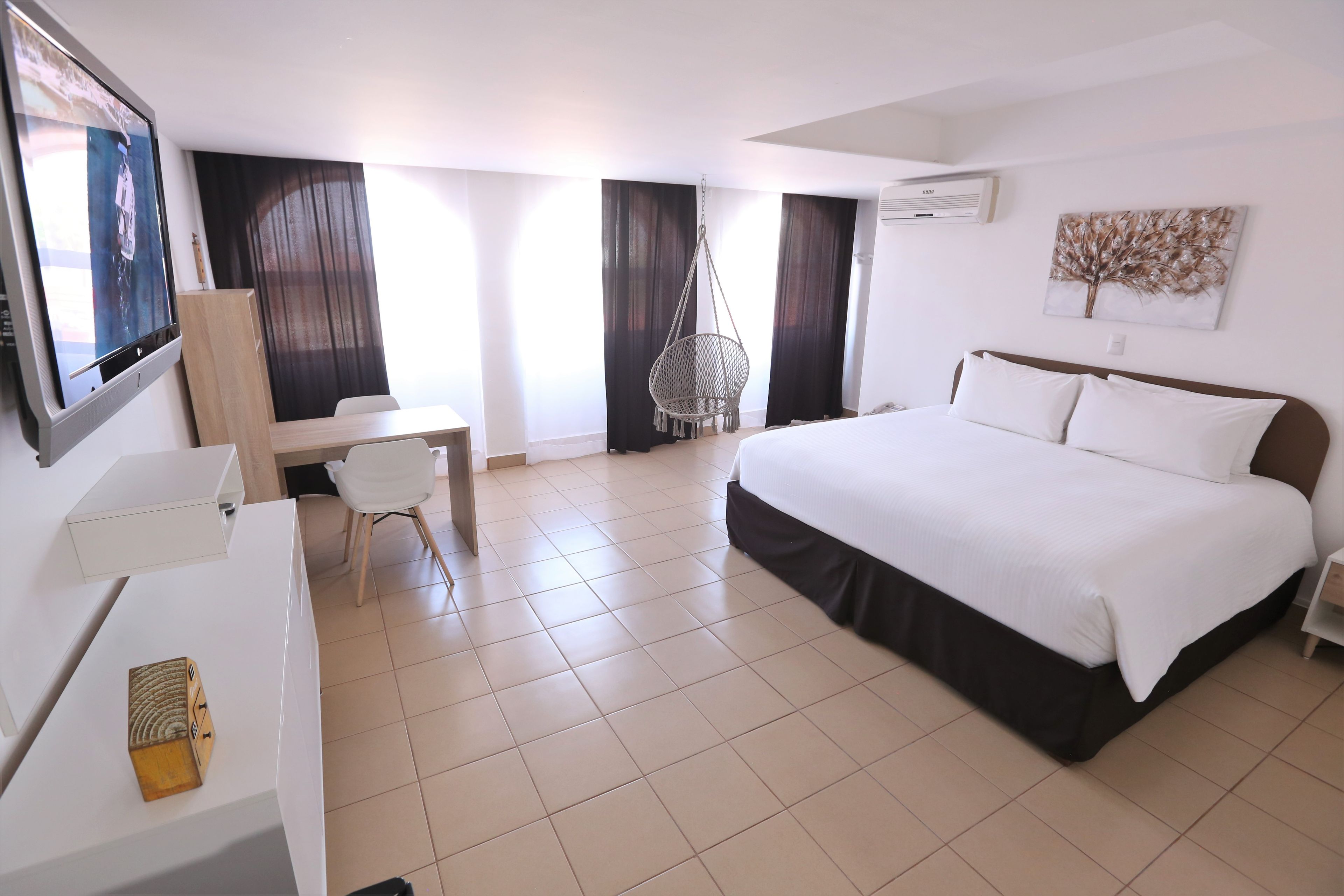 Habitació d'hotel amb llit, escriptori, cadira i televisió.